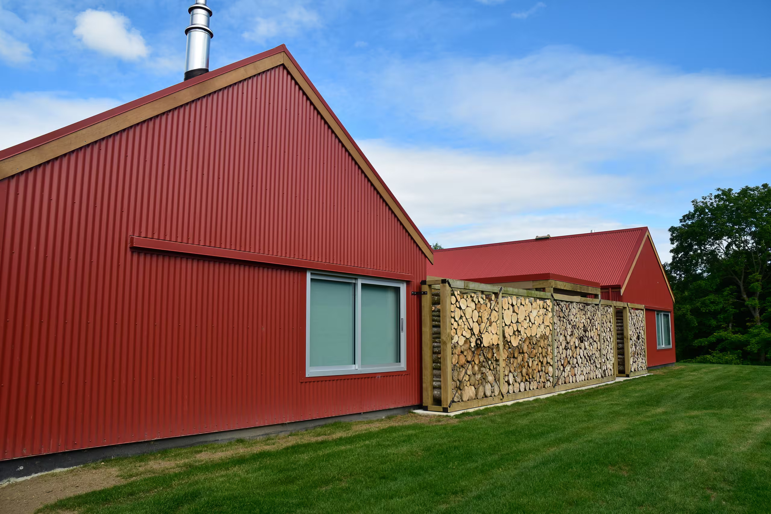 The red barn guesthouse, firewood stacked along its walls