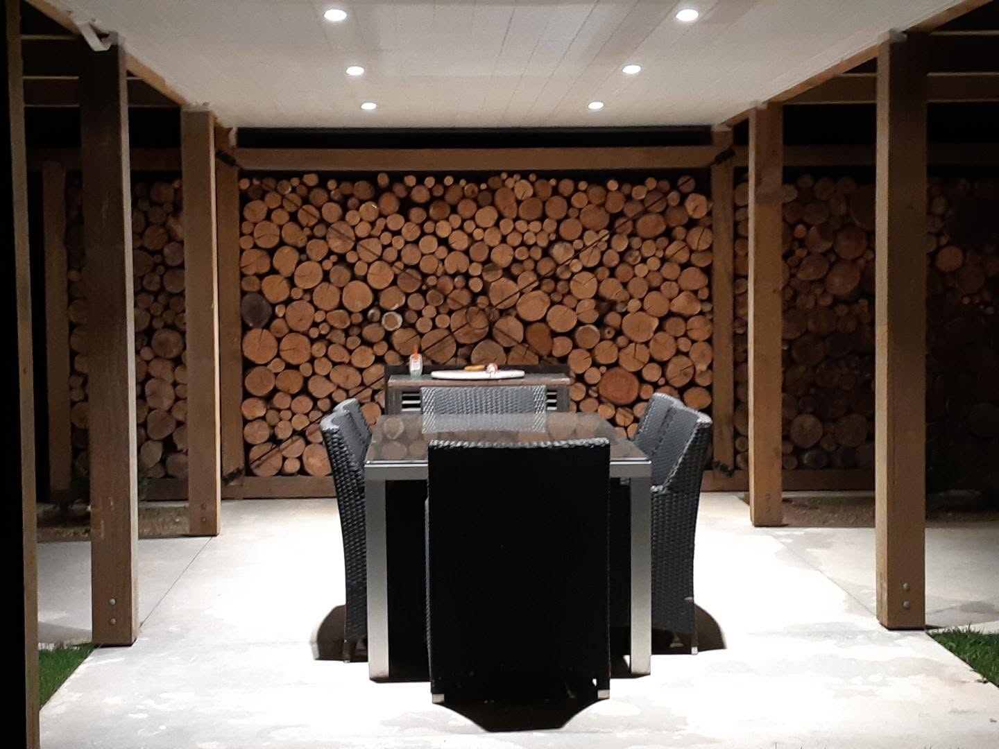 The outdoor dining area, walled with stacked firewood